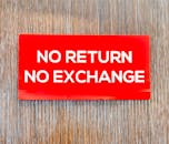 Bold red sign with 'No Return No Exchange' message on a wooden backdrop.